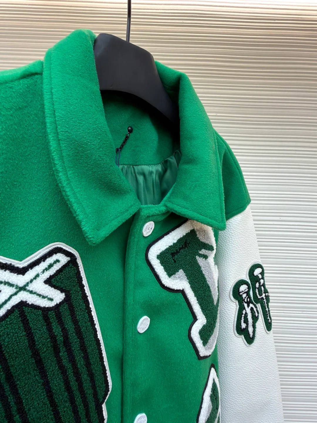 LOUIS VUITTON Loose long-sleeved baseball jersey with monogram pattern ●Original version: Purchased and developed for 29999 ●Item number: 1682254-C10 ●Fabric: cotton fabric ●Technology: embroidery production ●Color: green ●Version: fitted version ●Weight: about 1145 grams ●Size: 46-48-50-52 ●Description: The main body of this Louis Vuitton baseball jacket is made of high-count wool blended fabric. It has been processed by raising and carding processes. The fabric has a full velvety feel and is crisp and stylish. The green base color is made of worsted dyeing process. The color is pure and not easy to fade. The sleeves are spliced ​​with custom pebbled artificial leather, which has been embossed and softened. The texture is natural, flexible to the touch, and is scratch-resistant and wear-resistant. The letters and patterns decorated on the body are made of terry embroidery + appliqué embroidery composite technology. The terry embroidery coils are fluffy and three-dimensional, and the edges of the appliqué embroidery are overlocked to ensure accurate pattern splicing. The handwritten text is made using flat embroidery technology, with fine stitches and clear fonts. The placket is made of custom-made mother-of-pearl buttons, which are hand-polished and polished to have a warm luster; the ribbed neckline and hem are made of spandex blended material, which has good resilience and is not easy to loosen. The overall design uses three-dimensional tailoring and hand-sewing techniques to integrate a variety of materials and embroidery techniques to fully demonstrate the essence of haute couture garments. The overall wiring is straight and delicate, the fabric is comfortable and soft, and the color is consistent without color difference. It can be matched with the same style to create a fashionable look and control various occasions. Customized accessories, complete with three standards, same style for men and women!